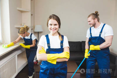 在工作過程中使用專業(yè)設(shè)備的清潔服務(wù)。專業(yè)的小廚房清潔, 沙發(fā)干洗, 窗戶和地板清洗。穿制服、工作服和橡膠手套的男人和女人